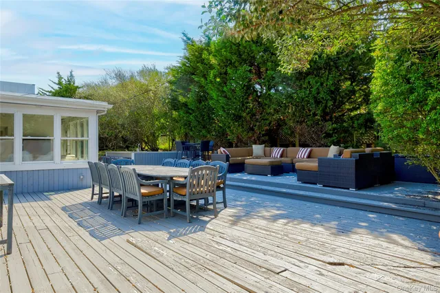 a view of a roof deck with table and chairs with wooden floor and fence
