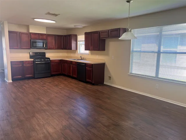 a large kitchen with stainless steel appliances granite countertop a stove a sink dishwasher a refrigerator and a oven with wooden floor