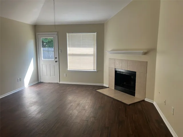 an empty room with wooden floor fireplace and windows