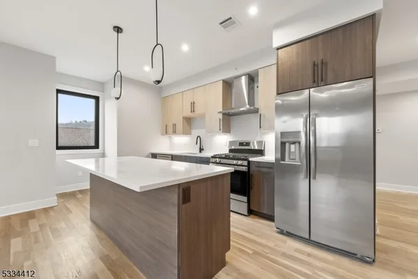 a kitchen with stainless steel appliances a refrigerator a sink and wooden floor