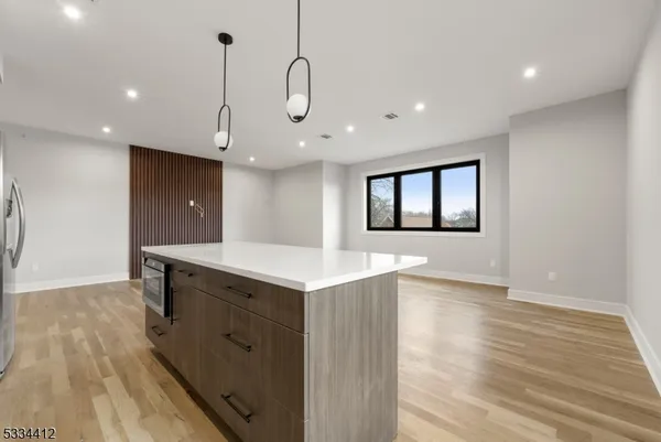 a large white kitchen with kitchen island a sink stainless steel appliances and cabinets