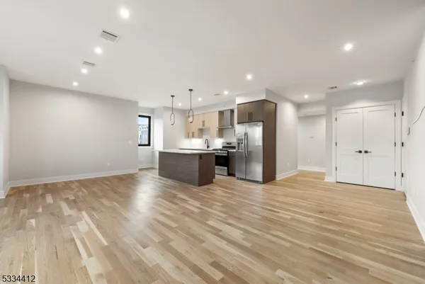 a view of kitchen with kitchen island a sink wooden floor and white cabinets