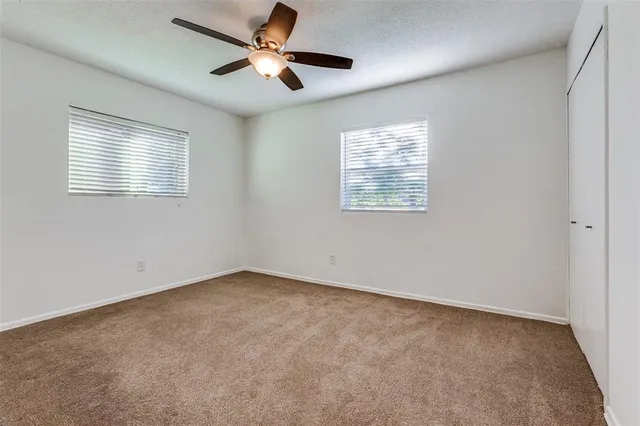 an empty room with windows and fan