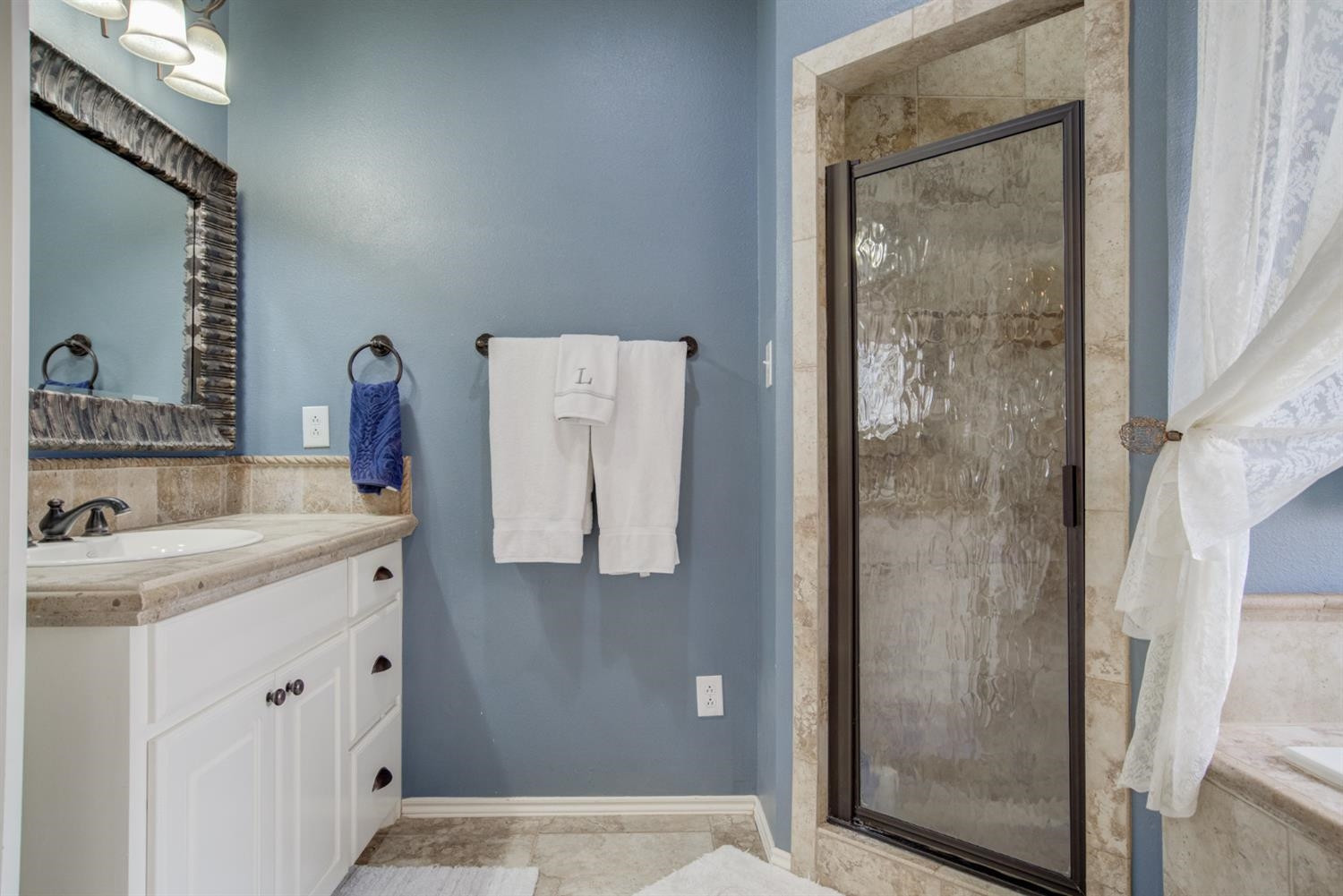 5904 110th Street Lubbock, TX 79424 - Photo 28 of 50 a bathroom with a shower sink and mirror