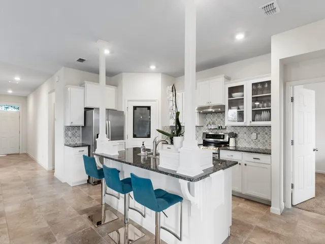 a kitchen with stainless steel appliances kitchen island granite countertop a stove a refrigerator a sink a dining table and chairs