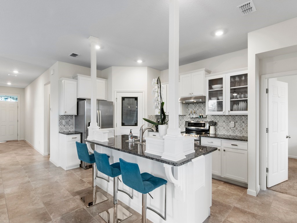 2040 Amazon Way Southwest Vero Beach, FL 32962 - Photo 3 of 35 a kitchen with stainless steel appliances kitchen island granite countertop a stove a refrigerator a sink a dining table and chairs