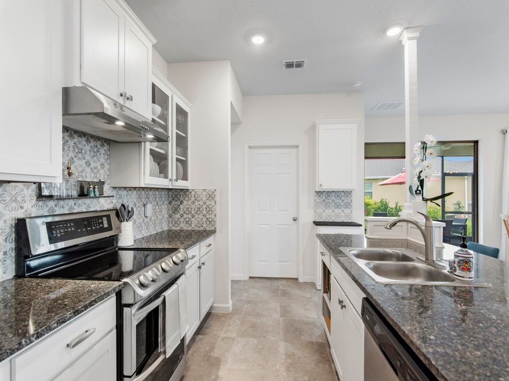 2040 Amazon Way Southwest Vero Beach, FL 32962 - Photo 6 of 35 a kitchen with stainless steel appliances granite countertop a sink stove and refrigerator
