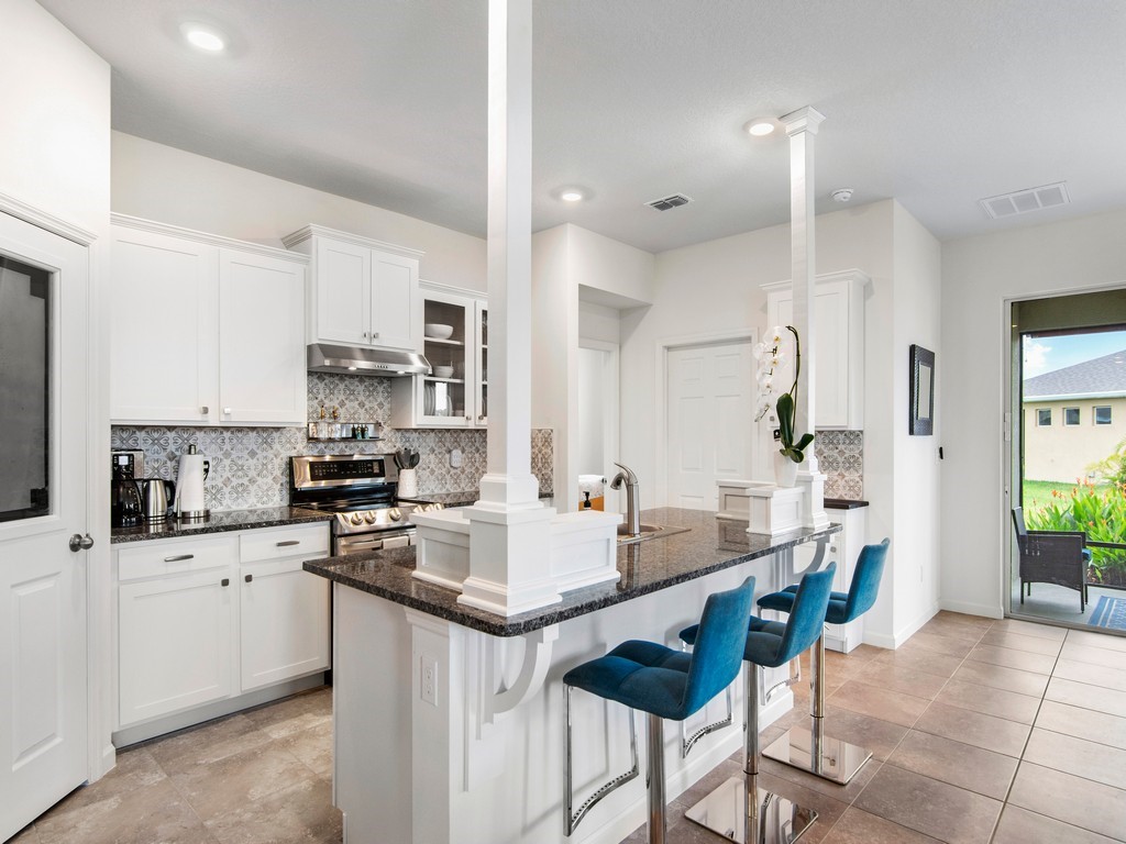 2040 Amazon Way Southwest Vero Beach, FL 32962 - Photo 7 of 35 a kitchen with stainless steel appliances a sink a stove a refrigerator cabinets and chairs
