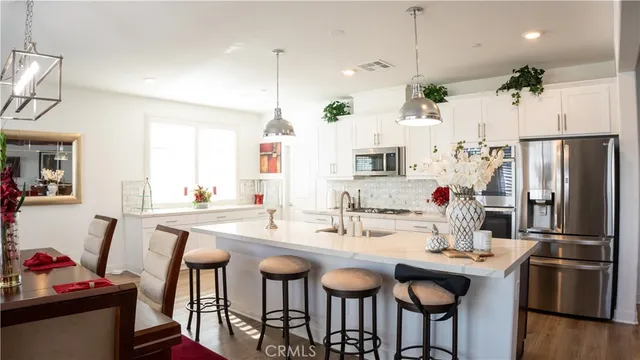 a kitchen with stainless steel appliances kitchen island a table chairs in it and wooden floors