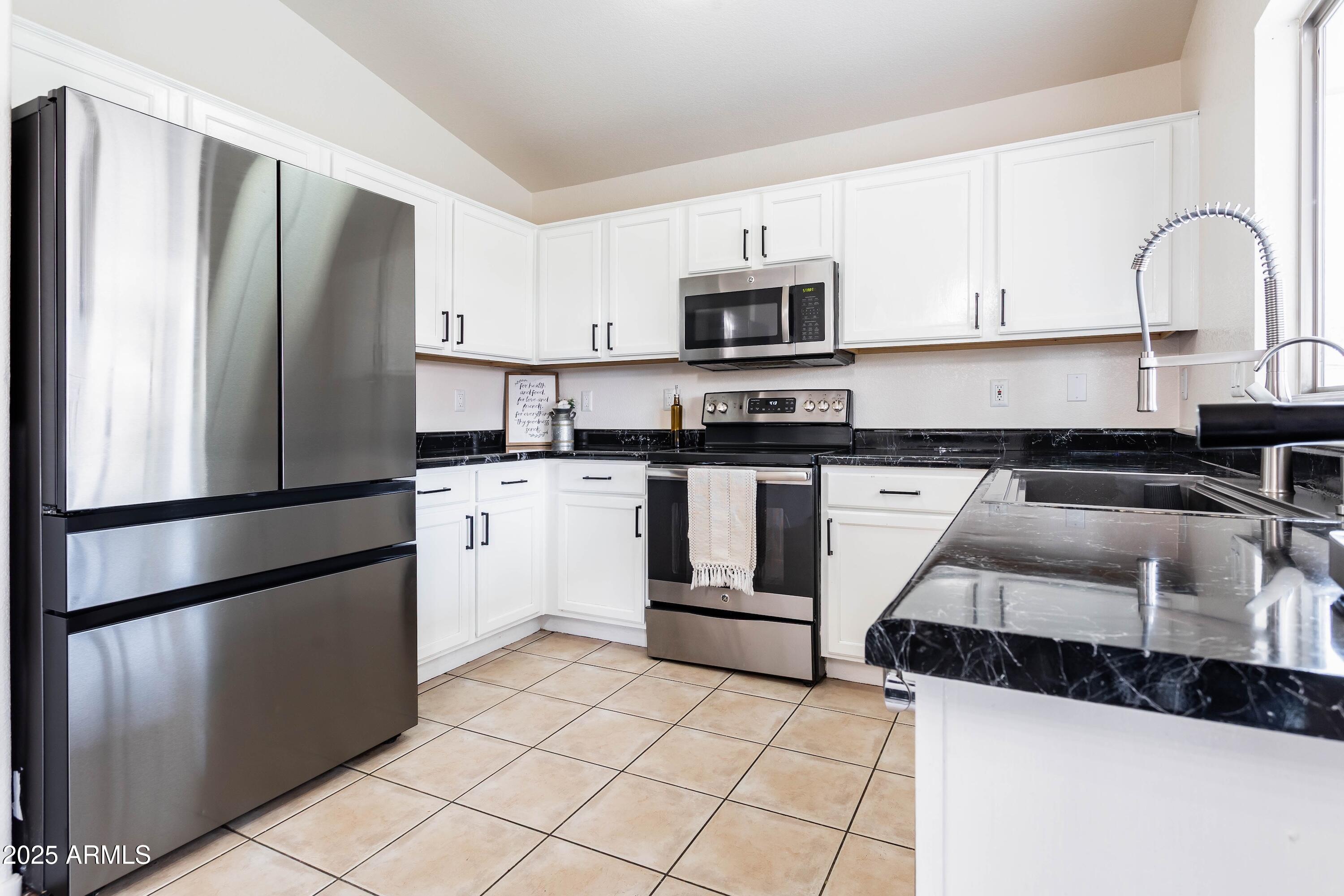 14931 West Redfield Road Surprise, AZ 85379 - Photo 4 of 26 a kitchen with stainless steel appliances granite countertop a refrigerator sink and white cabinets