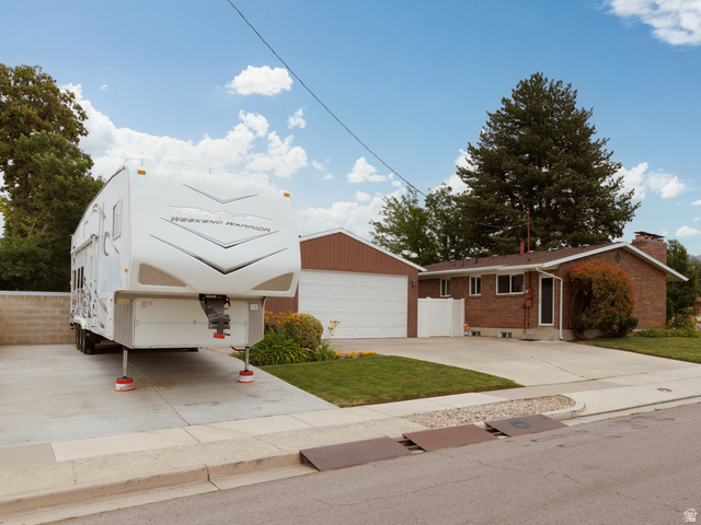 8252 Wood Street Midvale, UT 84047 - Photo 34 of 40 Brick exterior with white trim, a two-car garage, and an additional paved parking area