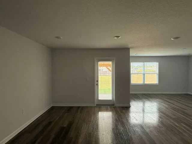 a view of an empty room and wooden floor and a window