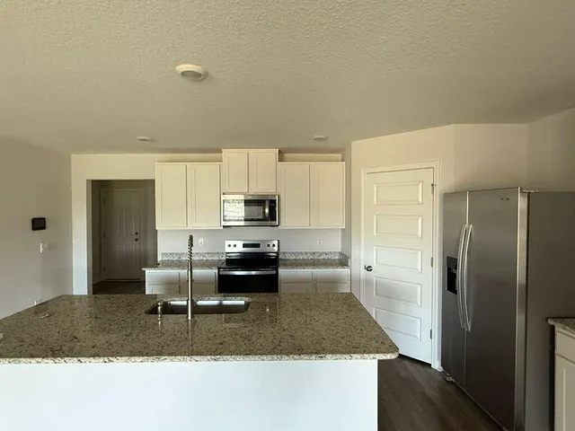 a kitchen with stainless steel appliances granite countertop a sink refrigerator and stove