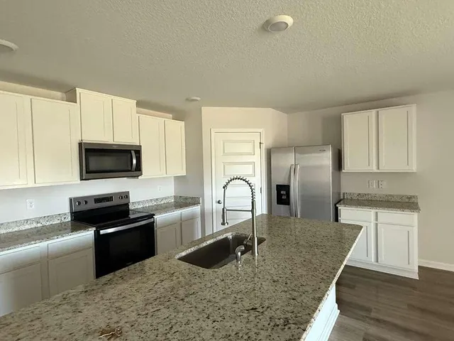 a kitchen with granite countertop a sink stainless steel appliances and cabinets