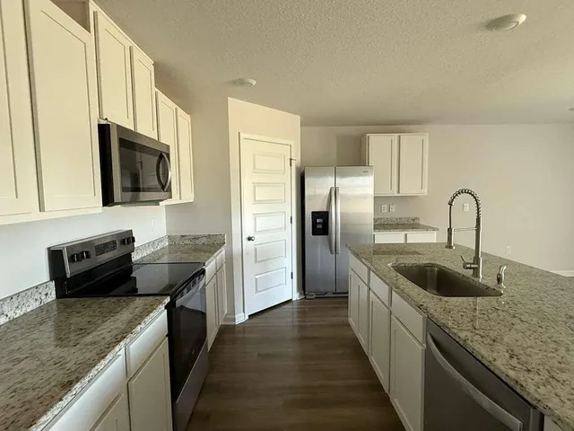 a kitchen with granite countertop a sink and a refrigerator