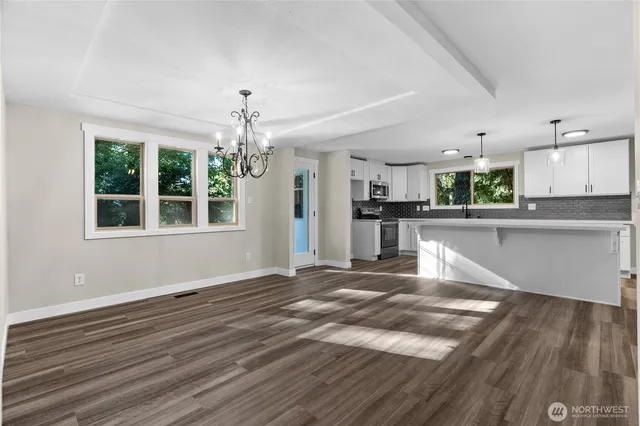 a view of a kitchen with kitchen island wooden floor and stainless steel appliances