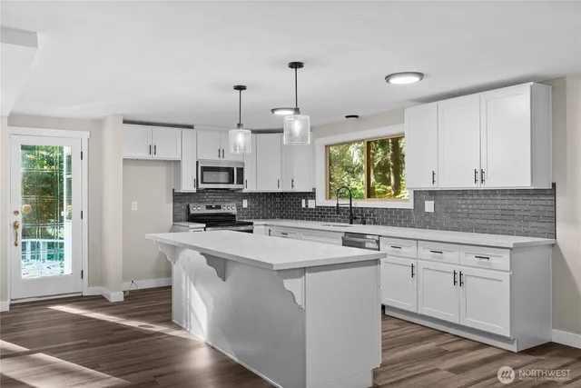 a kitchen with stainless steel appliances granite countertop a sink a stove a refrigerator and white cabinets