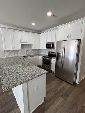 a kitchen with stainless steel appliances granite countertop a sink stove microwave and refrigerator