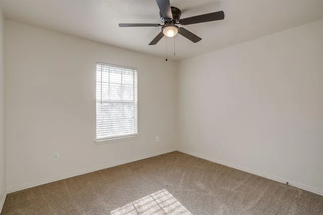 an empty room with a window and a fan