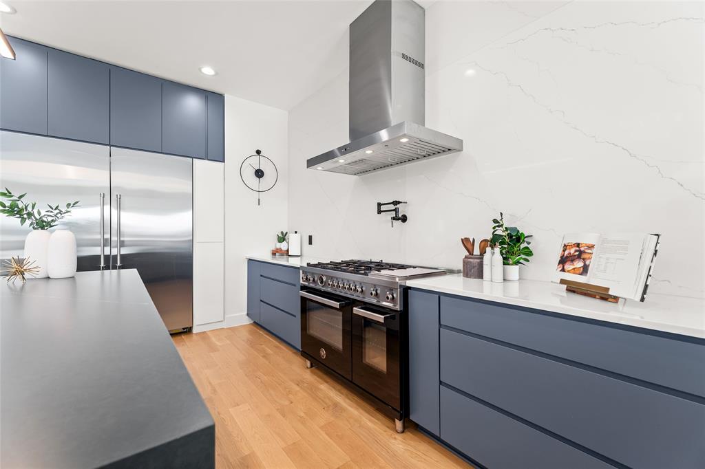 5020 Montgomery Road Midlothian, TX 76065 - Photo 11 of 40 Kitchen with modern cabinets, range hood, high quality appliances, blue cabinetry, and light wood finished floors