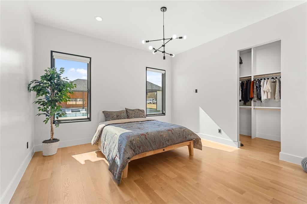 5020 Montgomery Road Midlothian, TX 76065 - Photo 27 of 40 Bedroom with a spacious closet, multiple windows, light wood-style floors, and hanging lights