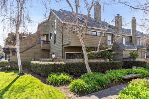 a view of a house with brick walls and a yard with plants