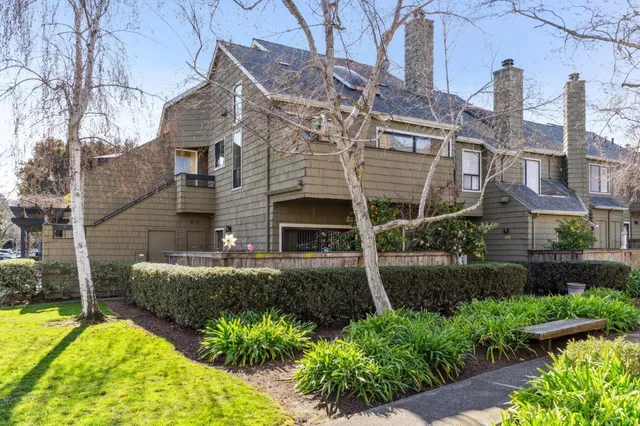 a view of a house with brick walls and a yard with plants