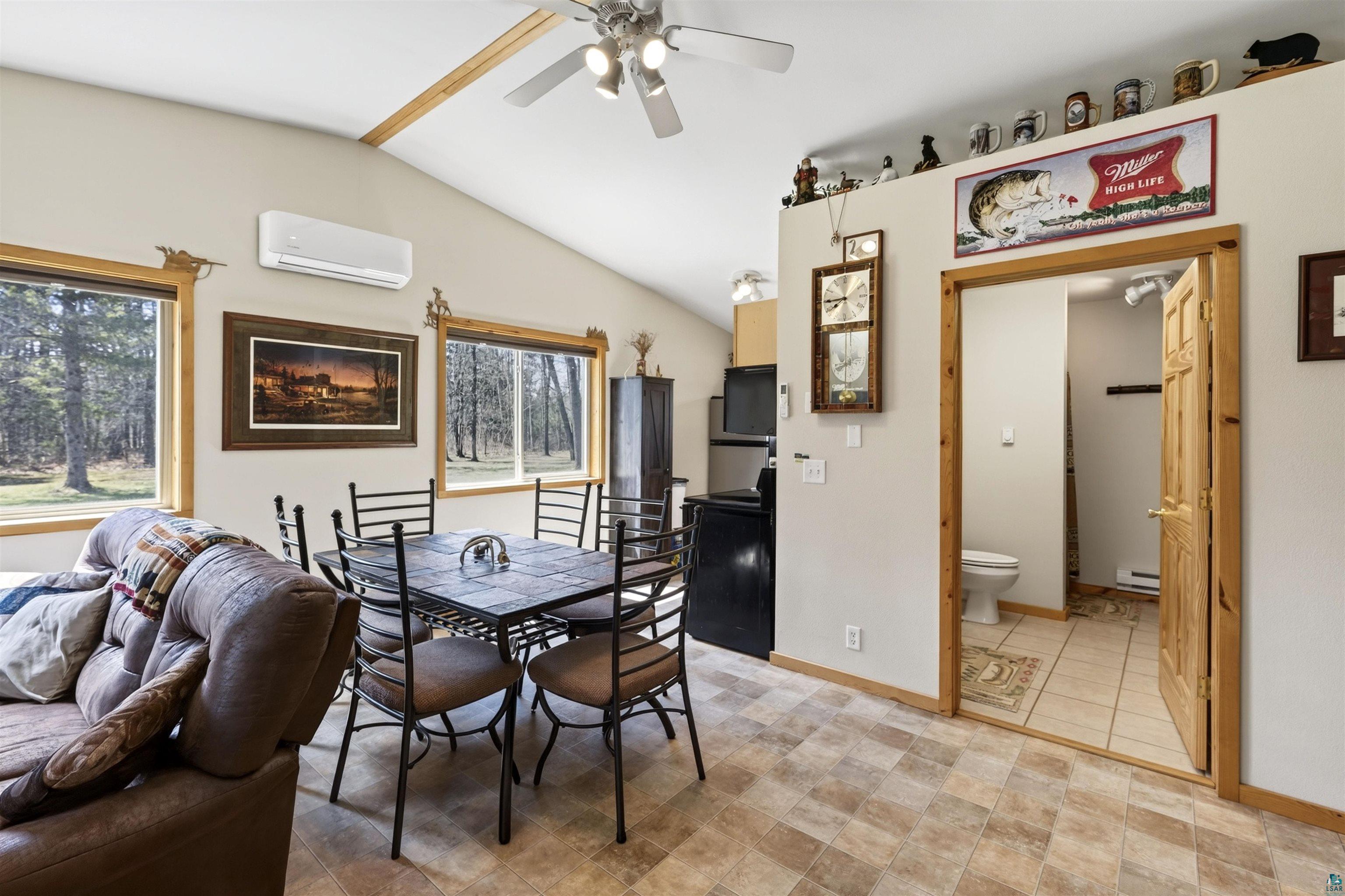 12235 East Crooked Lake Road Gordon, WI 54838 - Photo 8 of 48 Vaulted ceilings with exposed wood beams, wood-finish flooring, multiple windows providing exterior views, a ceiling fan, and a mini-split air conditioning unit