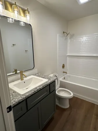 a bathroom with a granite countertop sink a toilet and a bathtub