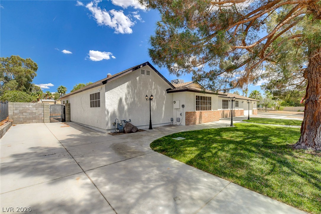 1810 Pinto Road Henderson, NV 89002 - Photo 7 of 53 Mature trees shade a manicured lawn alongside this home's extensive concrete driveway and charming brick accents.