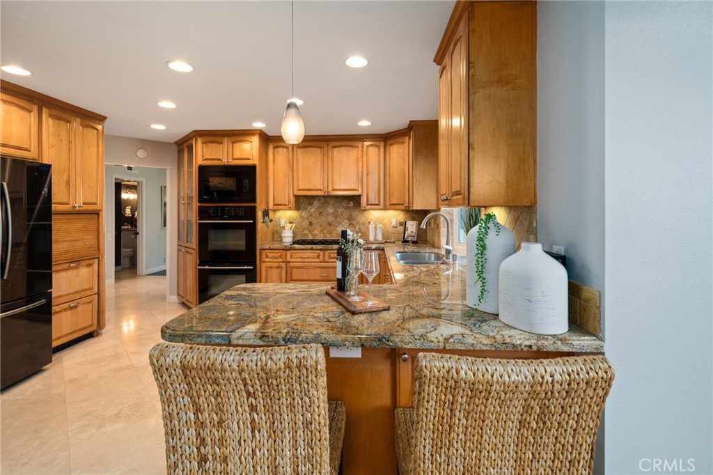 25695 La Cima Laguna Niguel, CA 92677 - Photo 13 of 52 a kitchen with kitchen island granite countertop a refrigerator a stove a oven a sink a dining table and chairs