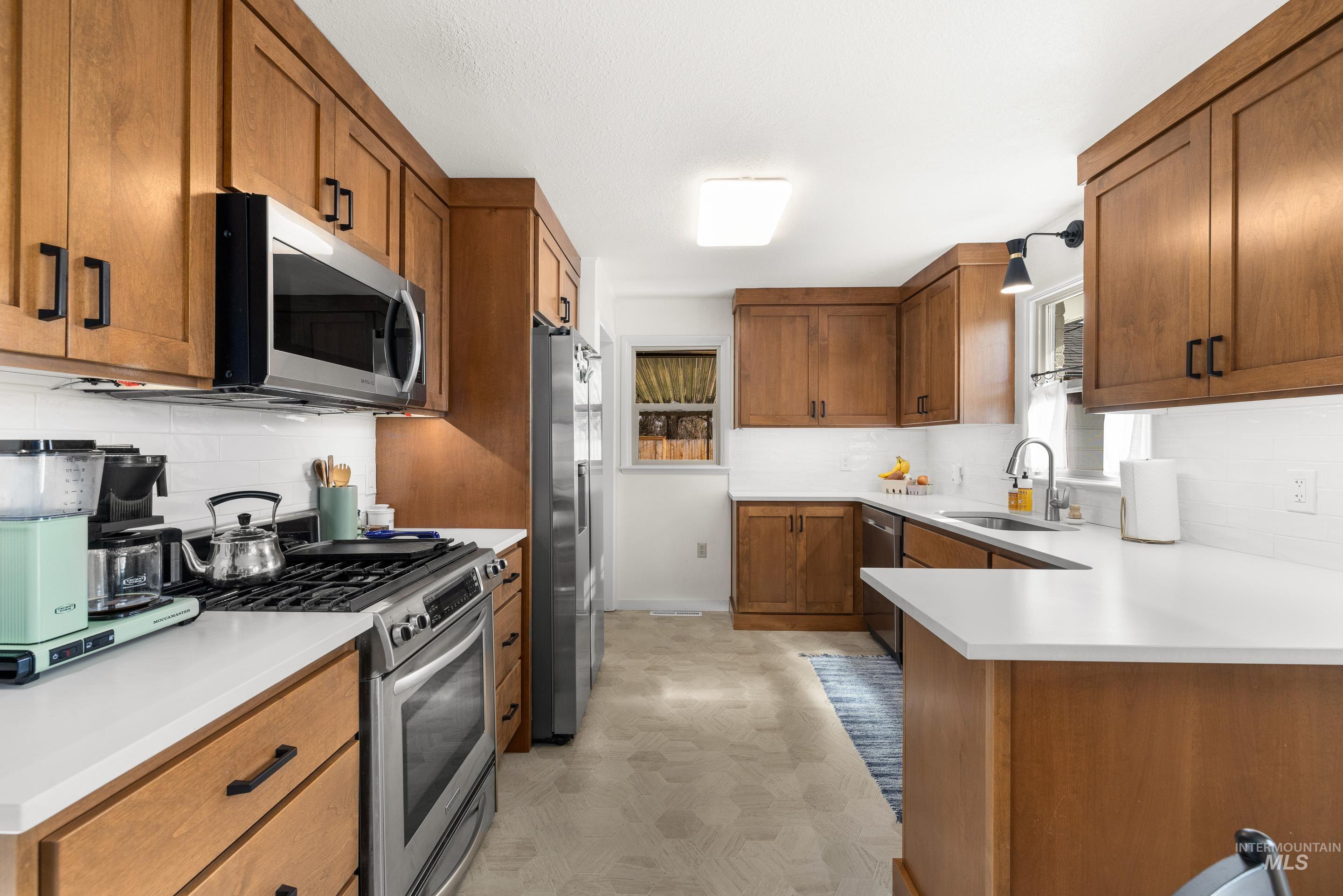 1010 Forrest Street Boise, ID 83705 - Photo 13 of 50 Kitchen featuring brown cabinetry, tasteful backsplash, appliances with stainless steel finishes, and light countertops