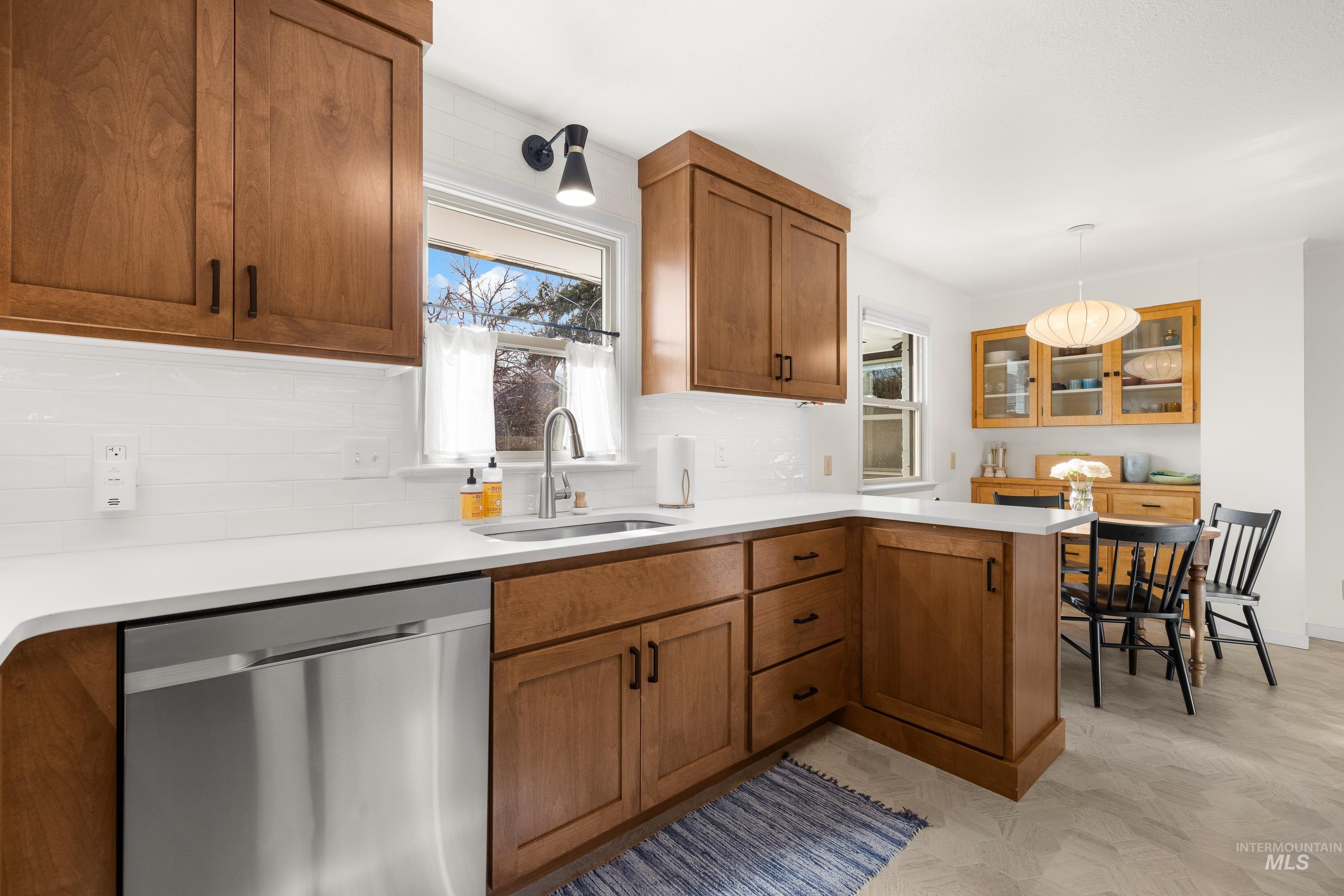 1010 Forrest Street Boise, ID 83705 - Photo 15 of 50 Kitchen with a peninsula, dishwasher, brown cabinets, and decorative backsplash