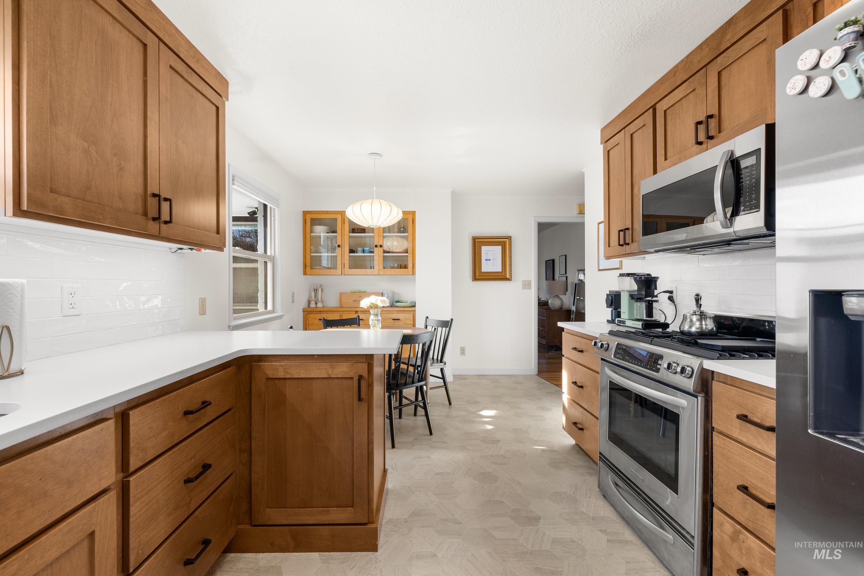 1010 Forrest Street Boise, ID 83705 - Photo 16 of 50 Kitchen with backsplash, appliances with stainless steel finishes, brown cabinets, and light countertops