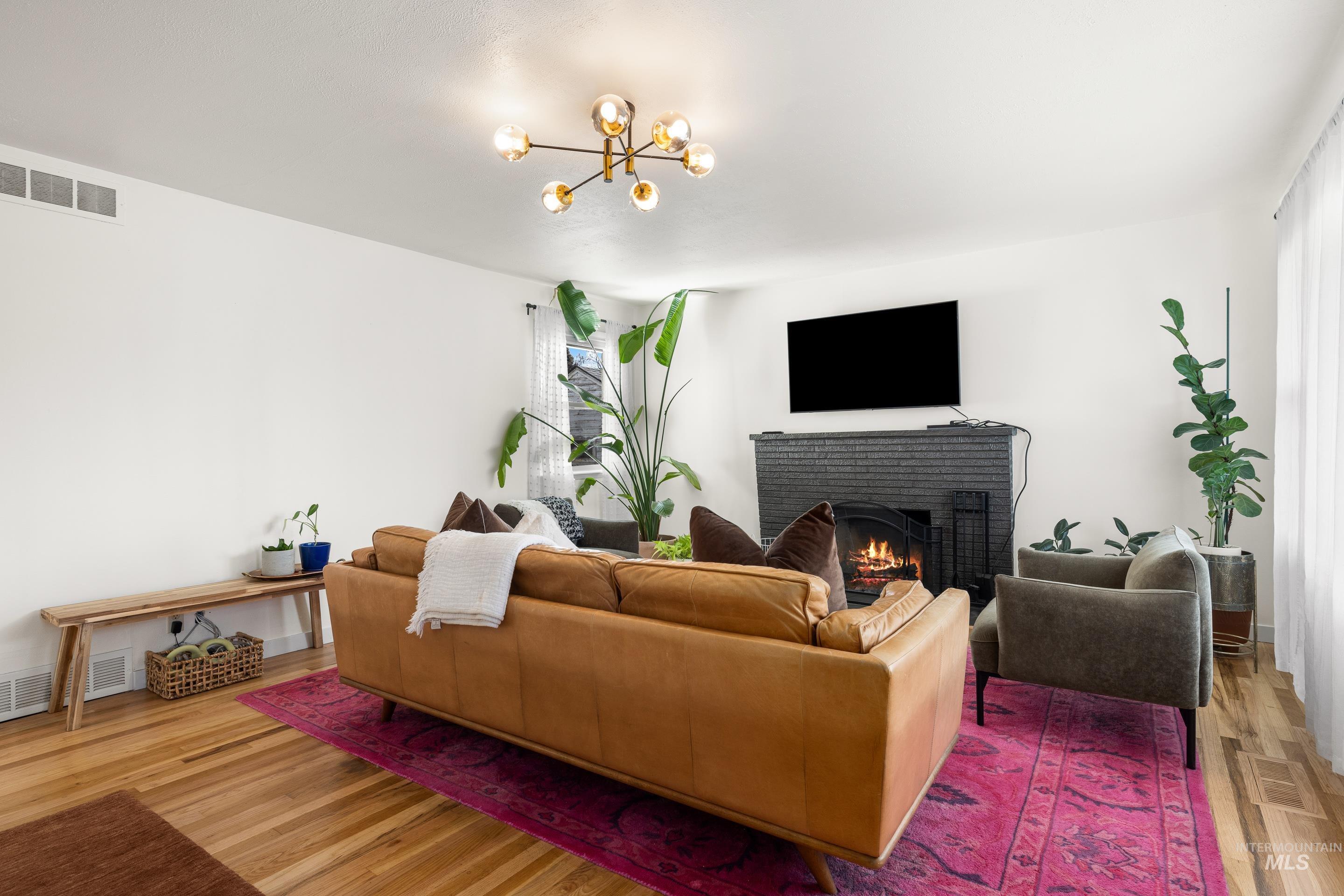 1010 Forrest Street Boise, ID 83705 - Photo 7 of 50 Living area featuring a brick fireplace, light wood-type flooring, and a chandelier
