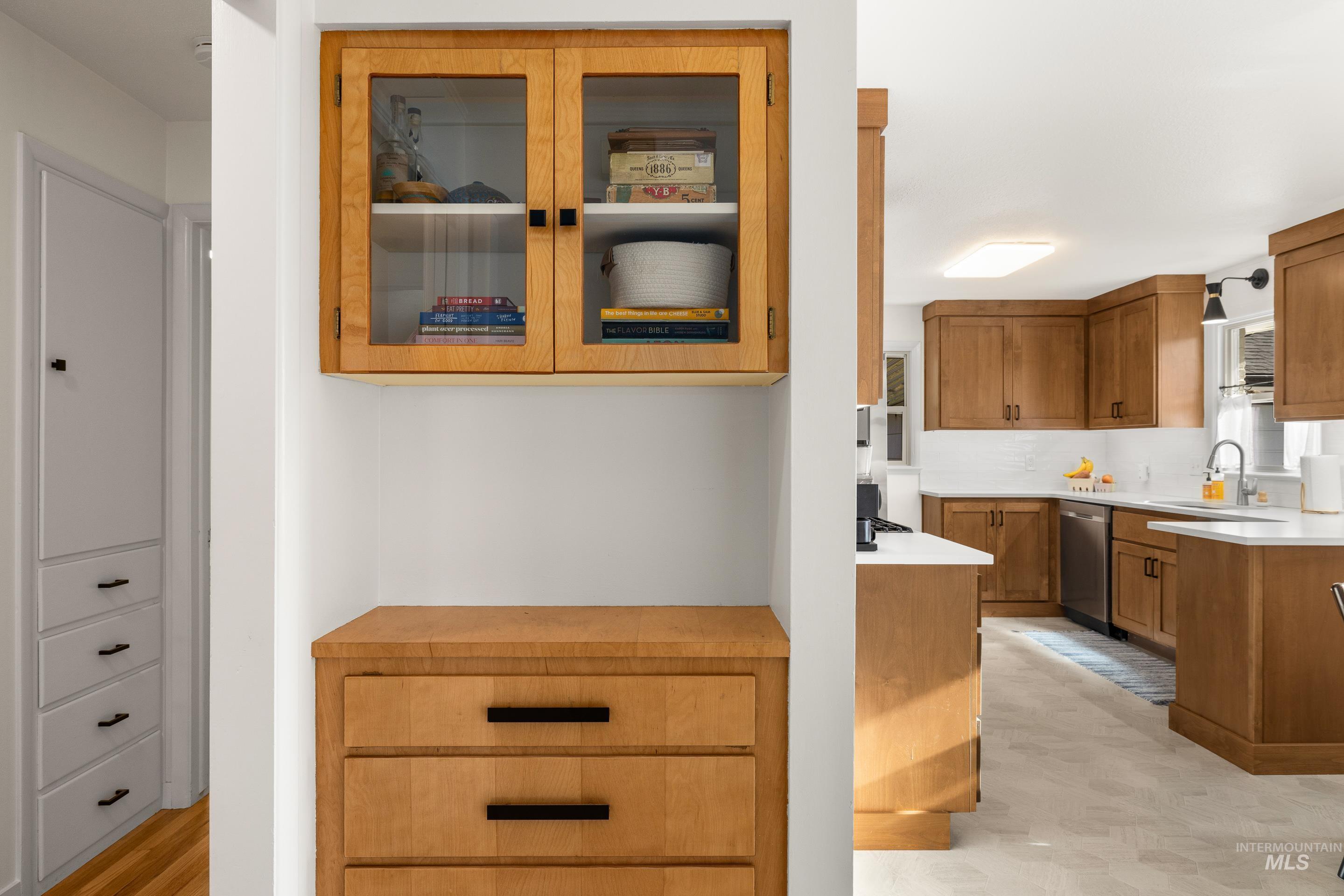 1010 Forrest Street Boise, ID 83705 - Photo 9 of 50 Kitchen featuring light countertops, brown cabinetry, glass insert cabinets, stainless steel dishwasher, and decorative backsplash