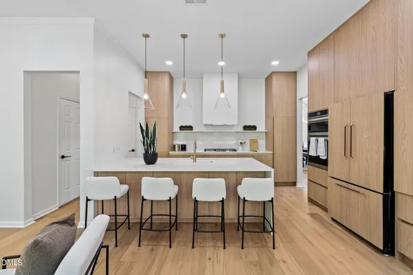 a kitchen with stainless steel appliances a dining table chairs refrigerator and sink
