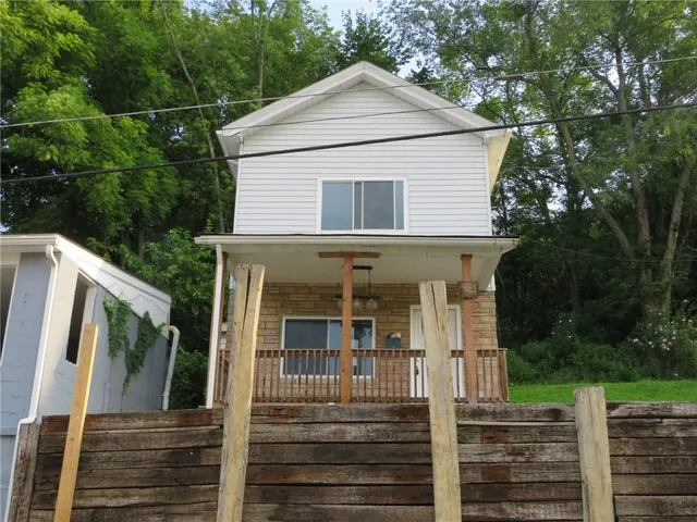 a view of a white house with large windows and a small yard