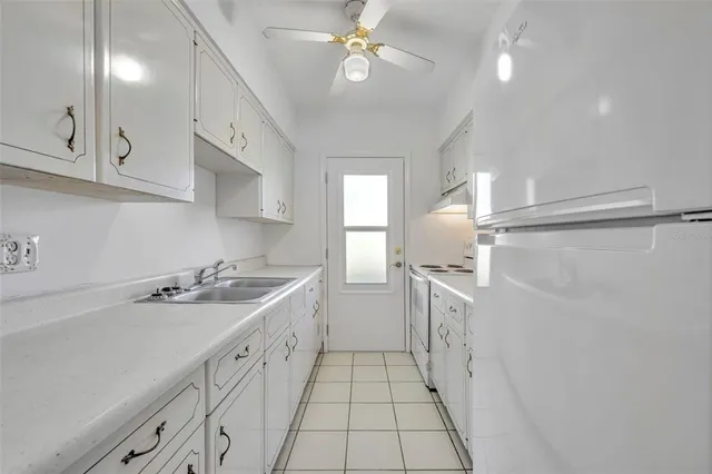 a kitchen with a sink a refrigerator and cabinets