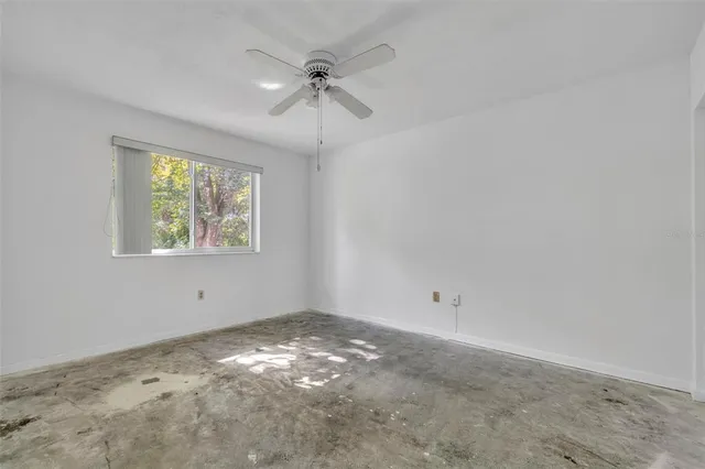 an empty room with windows and fan