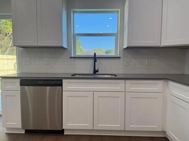 a kitchen with granite countertop white cabinets and a sink