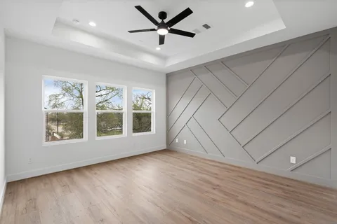 a view of empty room with wooden floor and fan