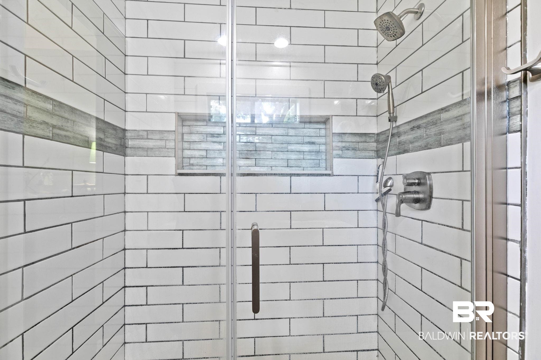 520 Juniper Place Drive Foley, AL 36535 - Photo 21 of 35 Frameless glass shower enclosure featuring subway tile walls with a decorative accent band and a recessed niche