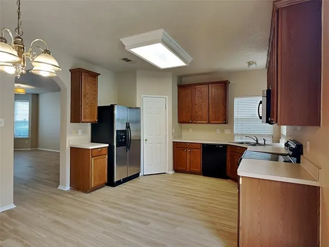 a kitchen with a sink wooden floor and stainless steel appliances