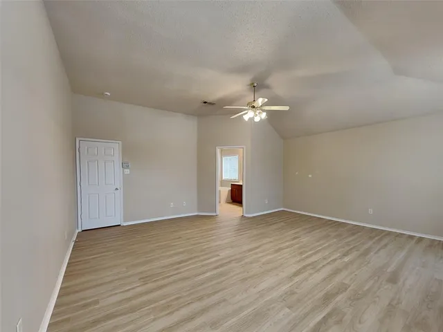 a view of an empty room with wooden floor and window