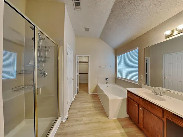a spacious bathroom with a tub sink shower and mirror