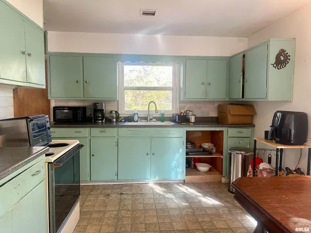 a kitchen with granite countertop a stove a sink and a cabinets