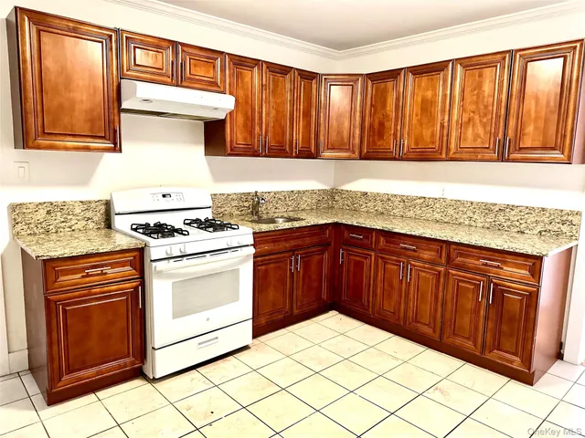 a kitchen with granite countertop a sink stove and cabinets