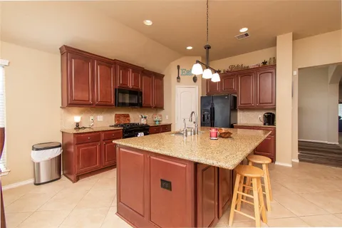 a kitchen with a stove a sink a microwave a dining table and chairs