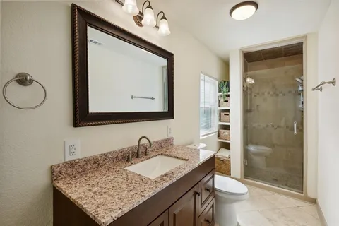 a bathroom with a granite countertop sink a toilet and shower